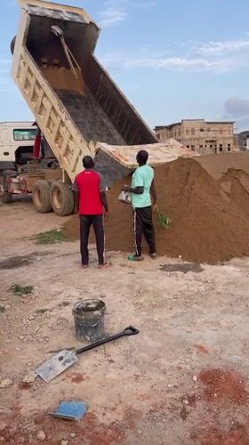 Construction workers oversee sand delivery in Angwan Sayawa, Nigeria