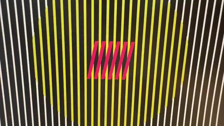 The media file is a close-up, abstract still image of a graphic design. The design features a series of vertical stripes in varying colors against a black background. In the center, there is a rectangular area containing several diagonal, bright pink stripes. Surrounding this central area, there are yellow vertical stripes that appear to form a circular or oval shape, creating an optical illusion. Towards the edges of the image, the vertical stripes are white. There is no discernible text, people, or scene in the traditional sense. The image appears to be a static visual, possibly part of a larger artwork, print, or digital display. The lighting is even, suggesting an indoor setting, and there are no indicators of time of day or weather. The overall impression is one of geometric abstraction and optical art. The location context of Las Rozas de Madrid, Spain, does not provide any visual cues within the image itself.