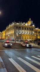 Police cars with lights stationed outside illuminated building
