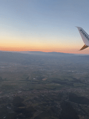 Passenger films sunrise landscape from airplane over Italian countryside