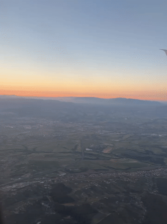 Passenger films sunrise landscape from airplane over Italian countryside