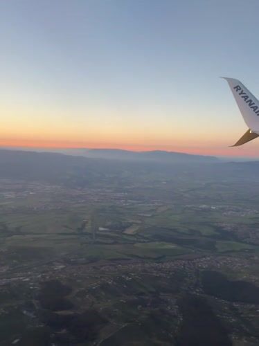 Passenger films sunrise landscape from airplane over Italian countryside