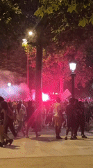 Crowd gathers with red flares on Paris street