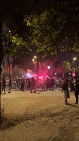 Crowd gathers with red flares on Paris street