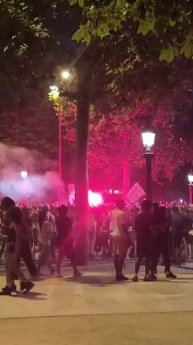 Crowd gathers with red flares on Paris street