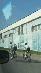 Two cyclists ride past mural-decorated building in Moscow