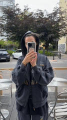 Woman photographs with phone on cafe patio, dog present