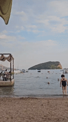 Lazy afternoon at a bay cafe, boats anchored, people in the water