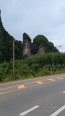 Morning traffic flows past karst cliffs in Khao Khram