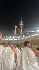 Pilgrims in ihram move through Mecca near the Kaaba at night