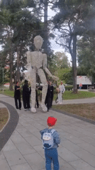 Giant wireframe puppet paraded through Jūrmala park by dark-clad crew