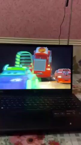 Here's a description of the video:

The video shows a laptop screen displaying a scene from the movie "Cars." Mack, the red semi-truck, is shown with the orange car Tex. Mack is leaving tire marks. Then Lightning McQueen is seen driving out of Mack.