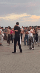 Couples dancing at a cobblestone plaza during sunset