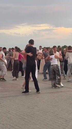 Couples dancing at a cobblestone plaza during sunset