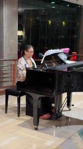 Woman plays grand piano in Bangkok lobby