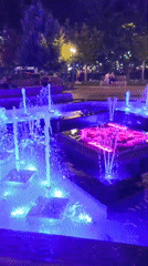 Lit-up fountain plaza at night with decorative lampposts