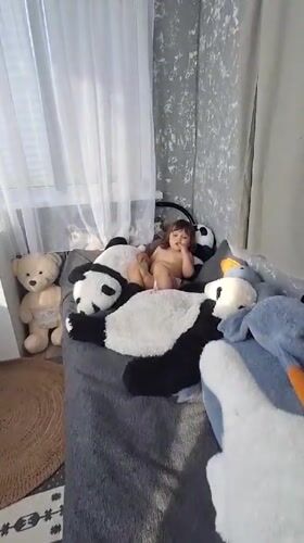 Toddler plays with stuffed pandas on bed in Russia