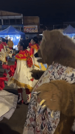 Nighttime street festival parade with elaborate costumed dancers in Arica