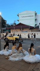 Women in formal gowns watch parade from Chiang Mai sidewalk