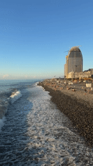 Crowded Batumi pebble beach with construction rising nearby