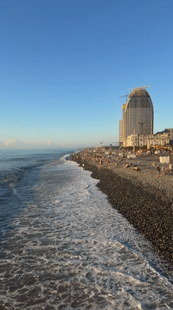 Crowded Batumi pebble beach with construction rising nearby