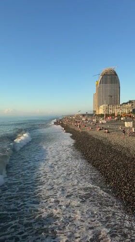 Crowded Batumi pebble beach with construction rising nearby