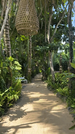 Woman walks through tropical resort pathways in Blahbatuh, Indonesia