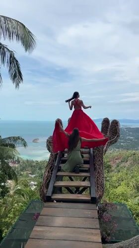 Women pose on hand-shaped viewing platform in Ko Samui