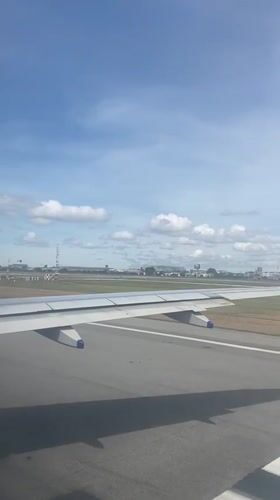 Passenger films wing view during aircraft movement in Thailand