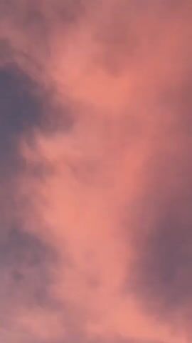 The video shows a sky with clouds. The clouds are pink and purple, and the sky is blue. The video is taken from a low angle, looking up at the sky. The clouds appear to be moving, but it is difficult to tell for sure. The video is blurry in some parts, but it is still possible to see the clouds and the sky.