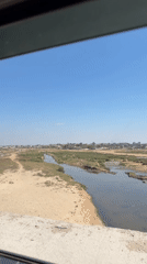 Arid river landscape near a distant settlement under clear skies