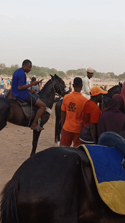Horseback riders gather in sandy field in Giginyu, Nigeria