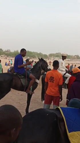 Horseback riders gather in sandy field in Giginyu, Nigeria