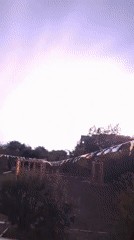 Nighttime outdoor scene with flags, lightning, and a roaming cat
