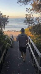 Beachgoer descends stairs to Bulli beach at sunset
