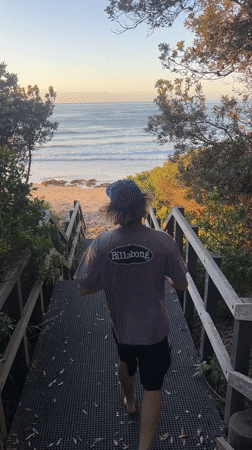 Beachgoer descends stairs to Bulli beach at sunset