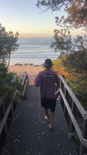 Beachgoer descends stairs to Bulli beach at sunset