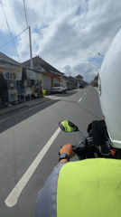Motorcyclist travels two-lane road in Mengwi, Indonesia morning hours