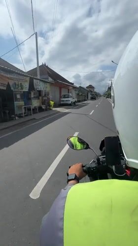 Motorcyclist travels two-lane road in Mengwi, Indonesia morning hours