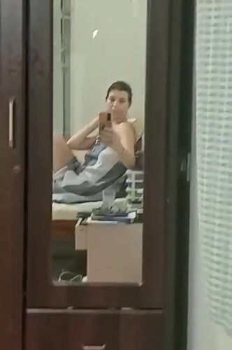 Woman takes mirror selfie on bed in Puttaparthi