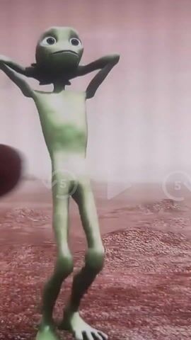 A green, animated alien with a large head is shown dancing against a dusty, pink landscape, likely on a TV screen. Its arms are often raised above its head, bending its legs rhythmically and changing positions.