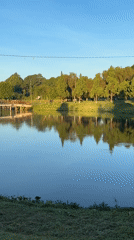 Pedestrians cross bridge over calm lake in Da Lat park