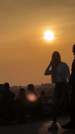 Street musician performs as crowds gather for sunset in Belgrade