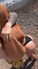 Bearded man films selfie, poses on mountain-view pebble beach