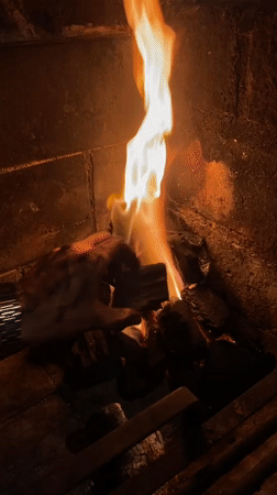 Person tends fireplace fire in Buenos Aires home