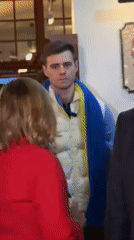 Indoor gathering in München includes Ukrainian-scarved man, business-dressed woman