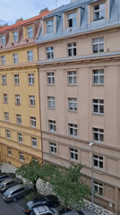 Street-level Prague neighborhood, yellow facades and a clock tower