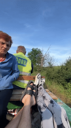 Group rides open utility trailer through rural Bulgarian village