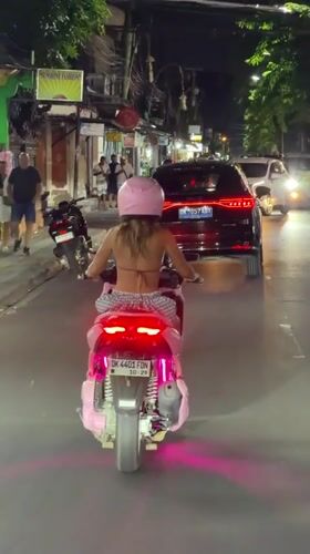 Pink scooter cruising Kuta streets after dark