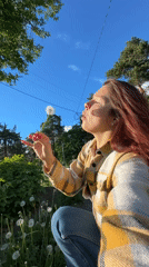 Woman blows dandelions in Vladimir field amid spring afternoon